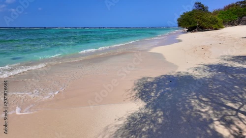static shot of ocean with calm waves reaching shore of sand beach on tropical Gili island Indonesia during sunny day, holidays, vacations, relax, paradise and tourism concept