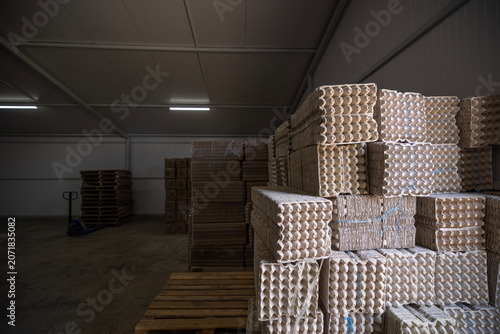 Fotografija Large stacks of empty molded pulp egg cartons are stored in an industrial warehouse facility