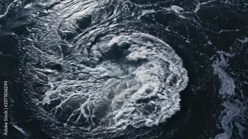 A powerful whirlpool swirls in the dark blue ocean water