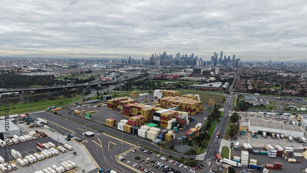 Fototapeta premium Melbourne city skyline rising above industrial shipping containers