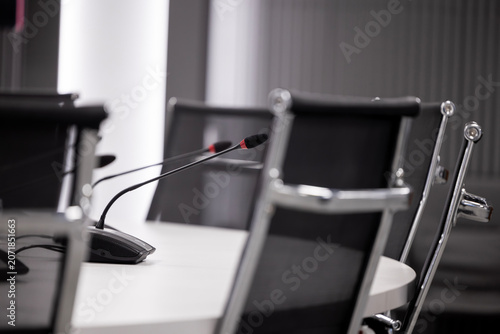 Fotografija An interior view of a meeting room setup, with multiple gooseneck microphones placed on a white conference table