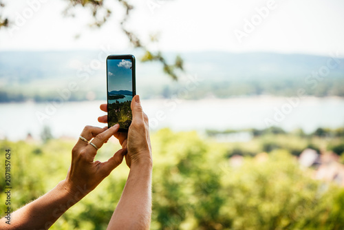 A person takes a mobile photo of a landscape while travelling.