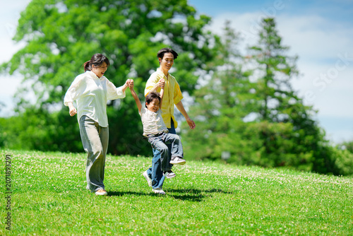 手を繋いで公園を歩く三人家族