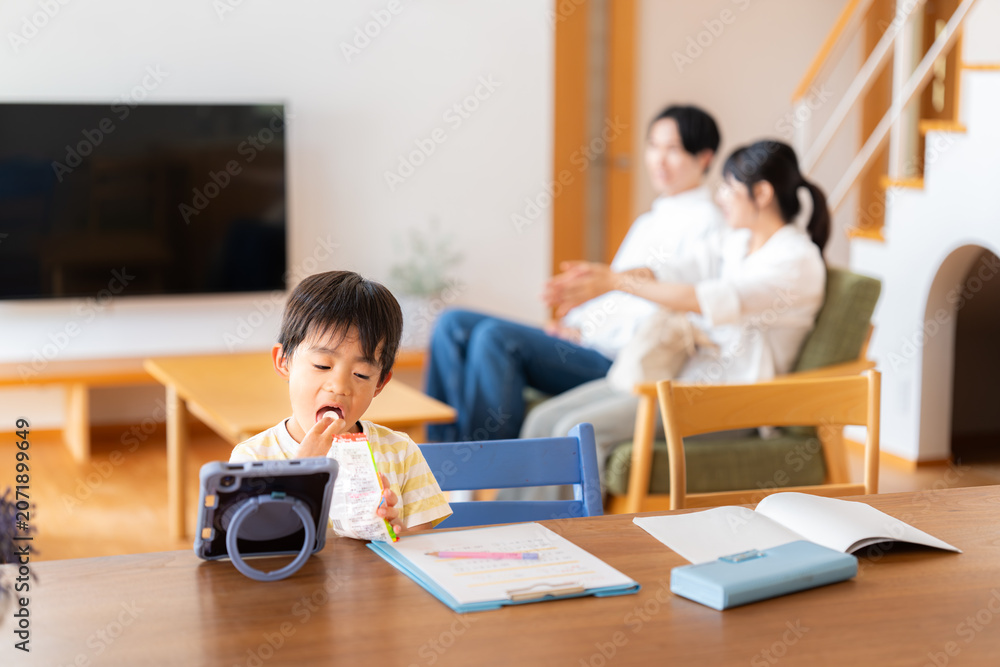 Fototapeta premium 勉強をサボって動画見ながらおやつを食べる男の子