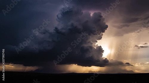 Dramatic storm clouds gather over a dark horizon at sunset