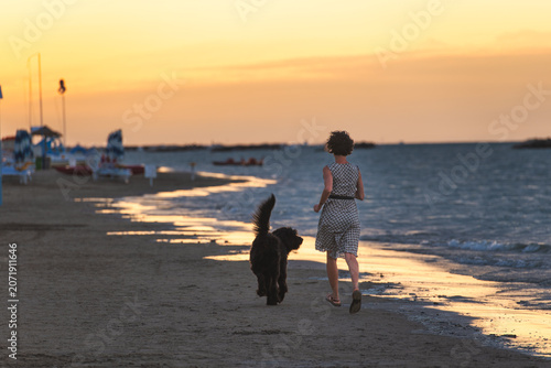 Woman Walking Her Dog on the Beach at Sunset