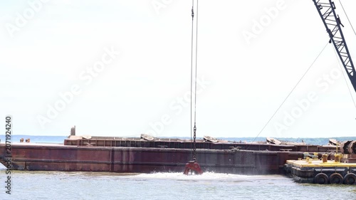 Claw from construction equipment splashes into the river to deepen the channel for passing ships