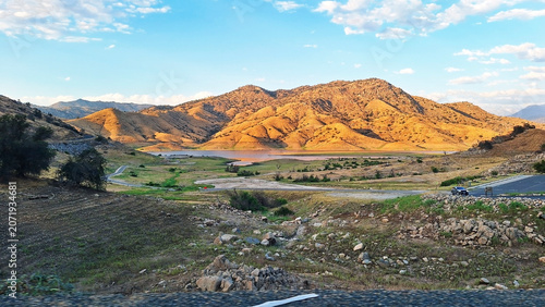 Scenic landscape view of Lemon Cove valley on Sierra Drive featuring golden hillsides, Lake and River Kaweah, native vegetation, rocky terrain, and clear blue sky. Sierra Nevada, California, USA.