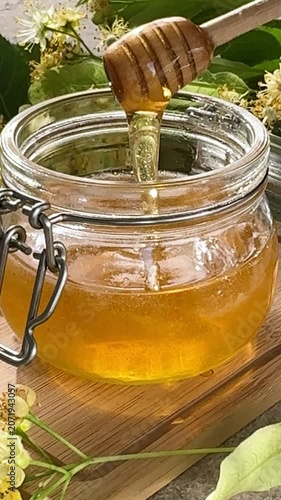 Linden honey dripping from dipper into jar