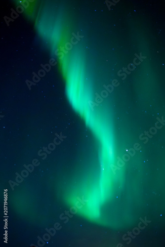 Green aurora lights glowing across a dark starry night sky