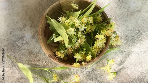 Linden flowers rotating in a wooden bowl for herbal tea preparation