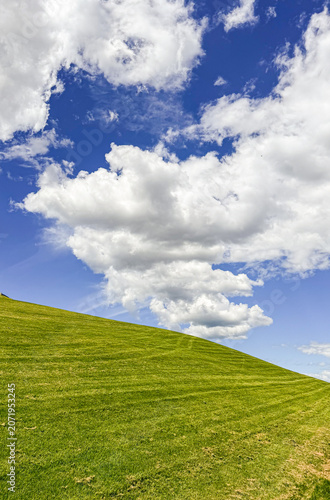 Bright clouds and green hill under blue sky during daytime