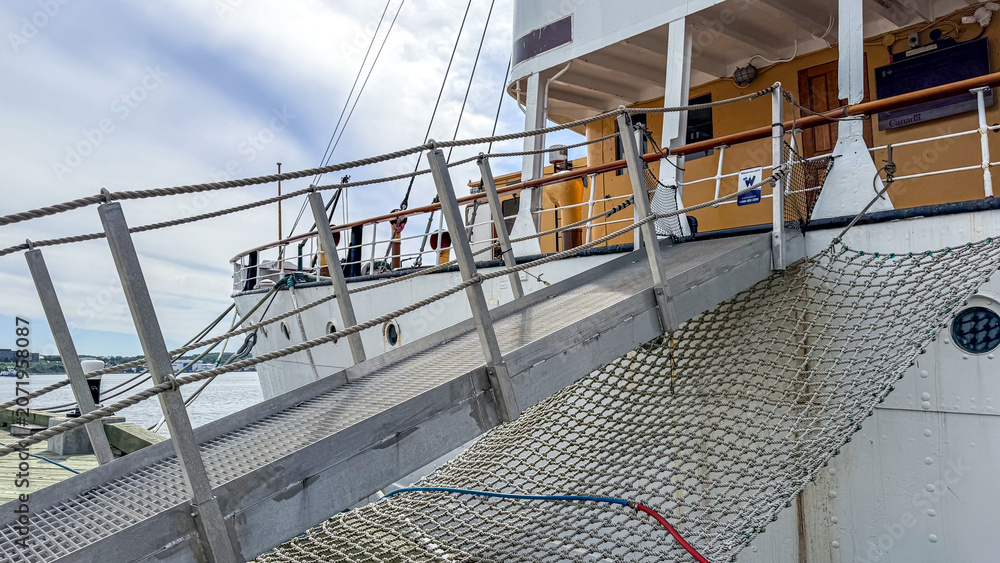 Fototapeta premium Docked ship with a ramp for boarding at a harbor during daytime