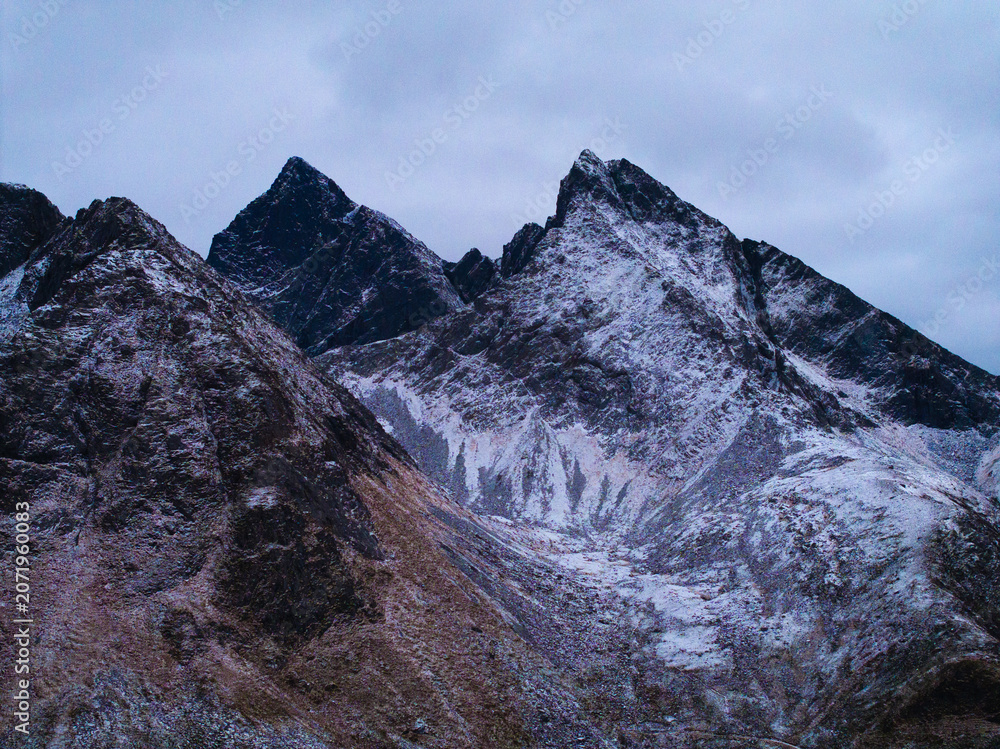 Obraz premium Snow covered mountain peaks under a cloudy sky