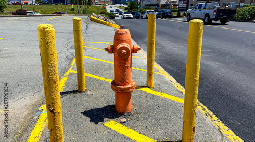 Fotografie Fire hydrant surrounded by yellow poles on a city street