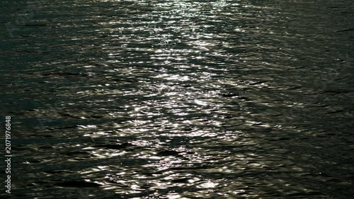Reflection of sunlight on the water surface of the lake at dusk at sunset. The water surface. The sun's rays twinkle on the water.	
