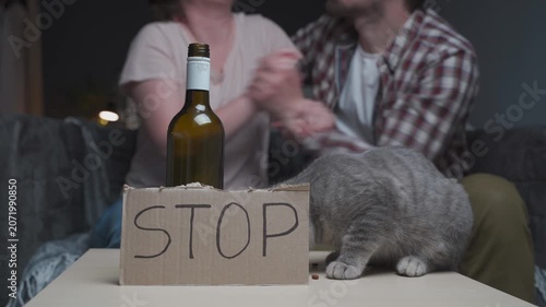 Close-up of a hungry cat feeding itself on a table next to an alcohol bottle, capturing a dramatic concept of family violence and severe pet neglect.