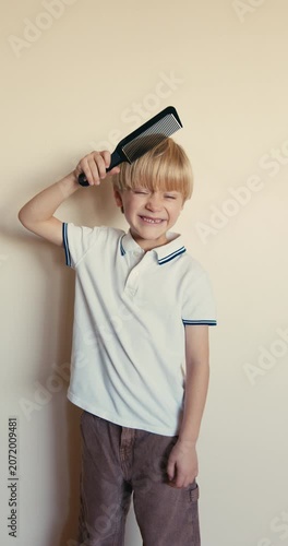 Cute blonde boy combing his hair