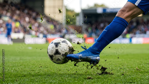 Fotografía Action shot of a soccer ball being kicked by a player on a grass pitch