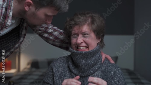 Dramatic footage of injured woman showing severe facial injuries and a missing tooth while her abusive, alcoholic spouse stands over her in dark room. Brutal impact of domestic violence and alcoholism