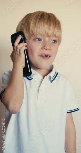 Expressive young boy talking on a smartphone