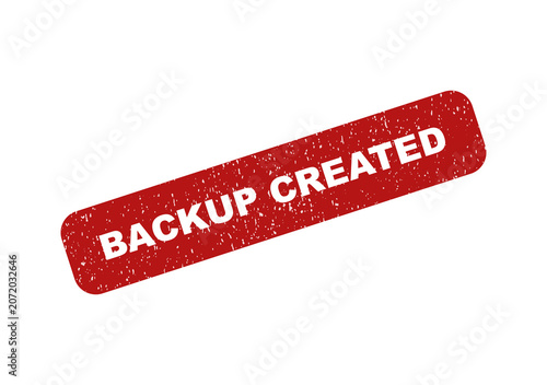 Red rubber stamp with the text backup created on a textured surface