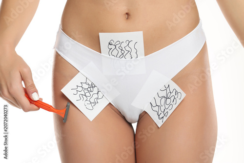 Fotografie Close-up of a woman’s bikini zone in white panties holding a razor with hair gro