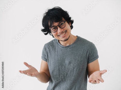 asian man cheerful person on simple backdrop communicates actively, enthusiastic asian man makes expressive gestures with open hands on minimalistic isolated on white background