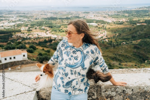 Woman relaxing with dogs overlooking countryside landscape outdo