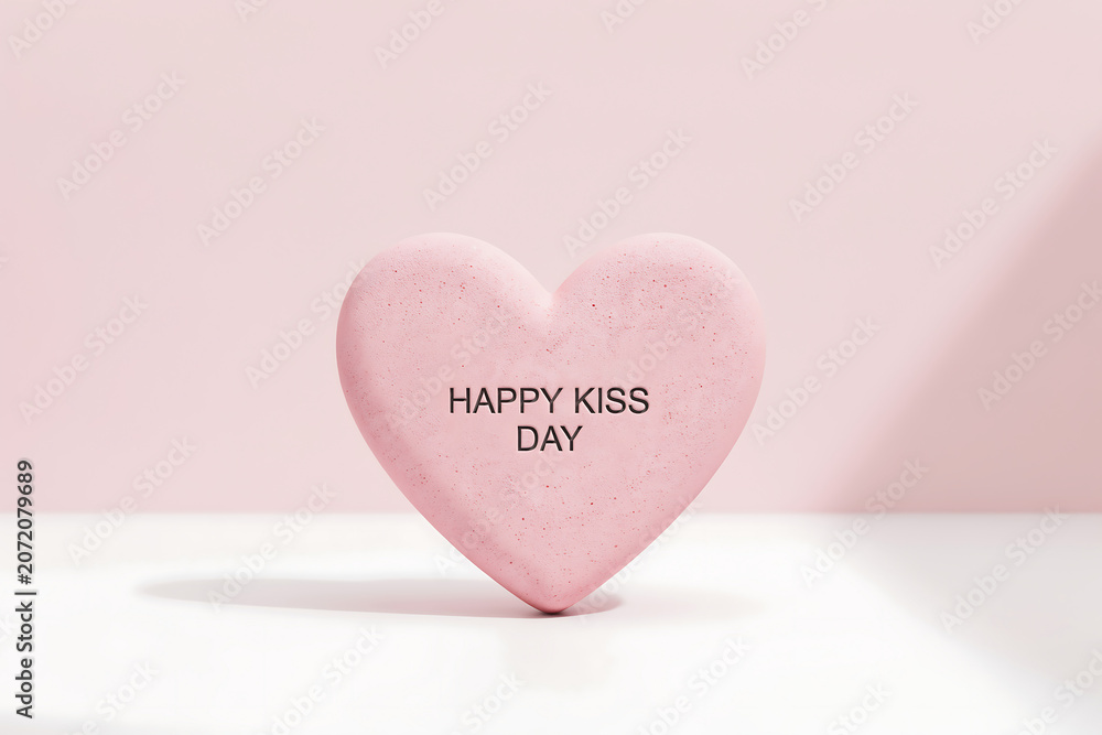 Fototapeta premium Pink heart shaped object with happy kiss day text on it in a pastel pink background