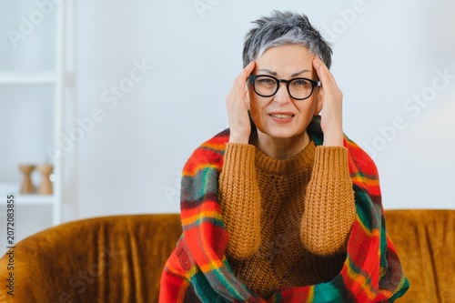 Fotografie Mature woman experiencing headache pain at home