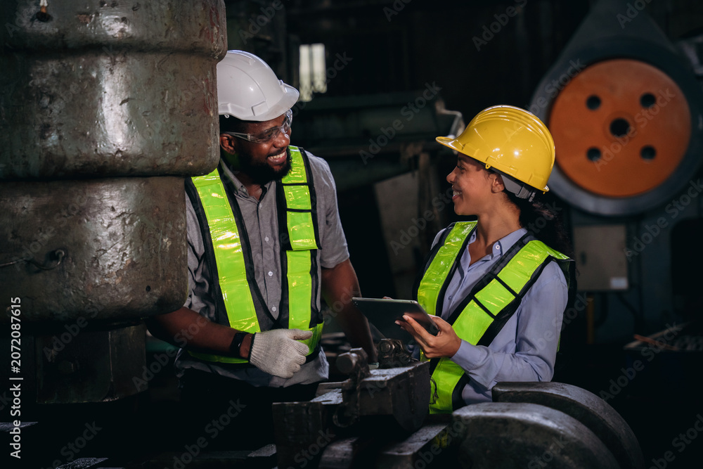 Fototapeta premium Group of professional mechanical technicians and engineers performing routine maintenance, inspecting components, and checking machinery on a factory plant site.