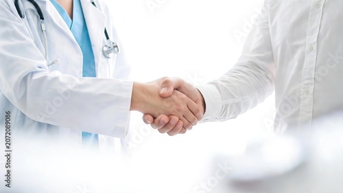 Two Doctors Shaking Hands in Clinical Setting - Medical Partnership &