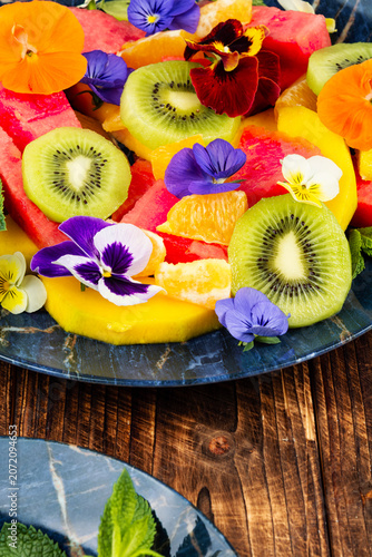 Exotic fruit salad decorated with edible flowers.