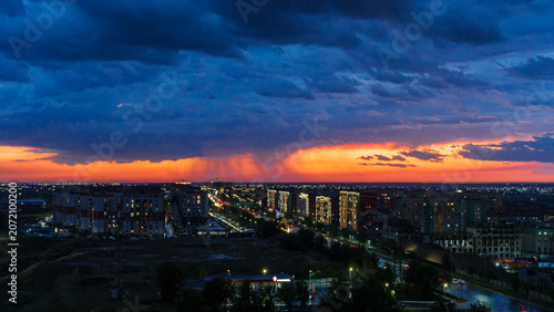 Foto Panoramic view of city skyline at sunset with dramatic clouds and rain in the di