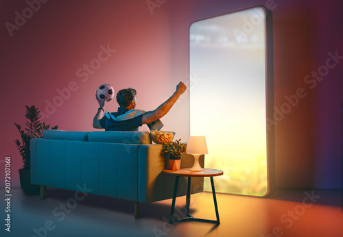 Man Watching Soccer on Giant Futuristic Screen at Home