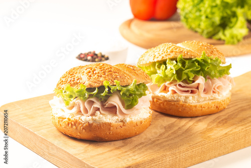 Sesame bagel sandwiches with turkey and chicken ham, cream cheese and fresh lettuce. Healthy food bun burger concept.
