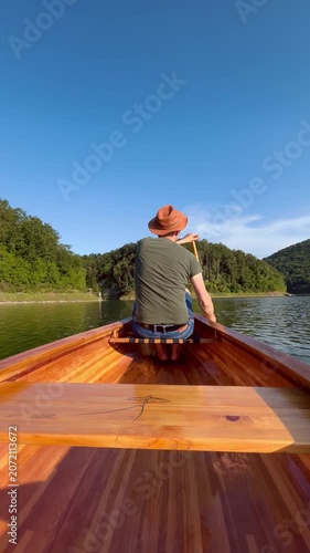 Man canoeing across peaceful lake