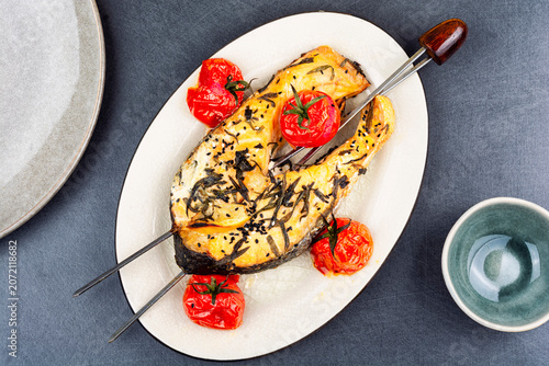 Grilled Salmon or Trout Steak Skewered with Roasted Cherry Tomatoes on White Plate