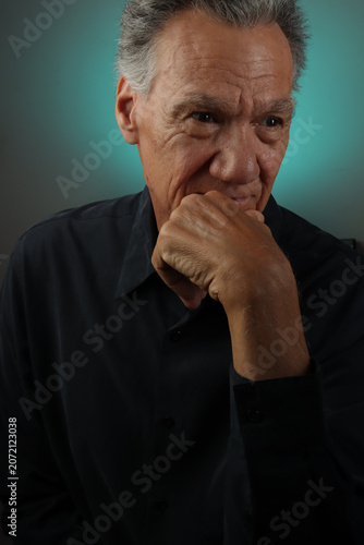 Older Senior Man looking serious with his hand on his chin in deep thought
