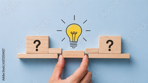 Hand placing a glowing lightbulb block to bridge the gap between question marks representing creative problem solving