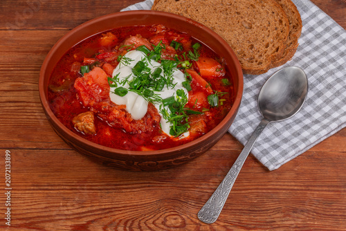 Valokuva Borscht serving with sour cream and potherbs on rustic table