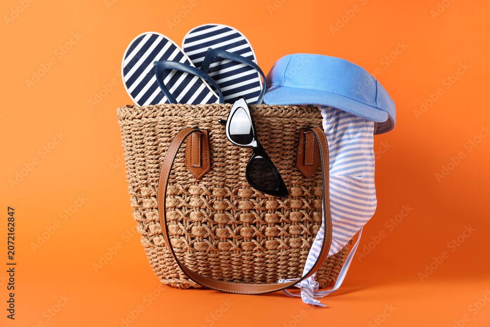 Fototapeta premium Bag with beach accessories on orange background