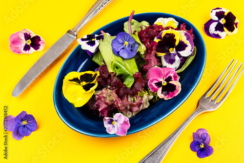 Colorful edible flower salad with mixed lettuce leaves