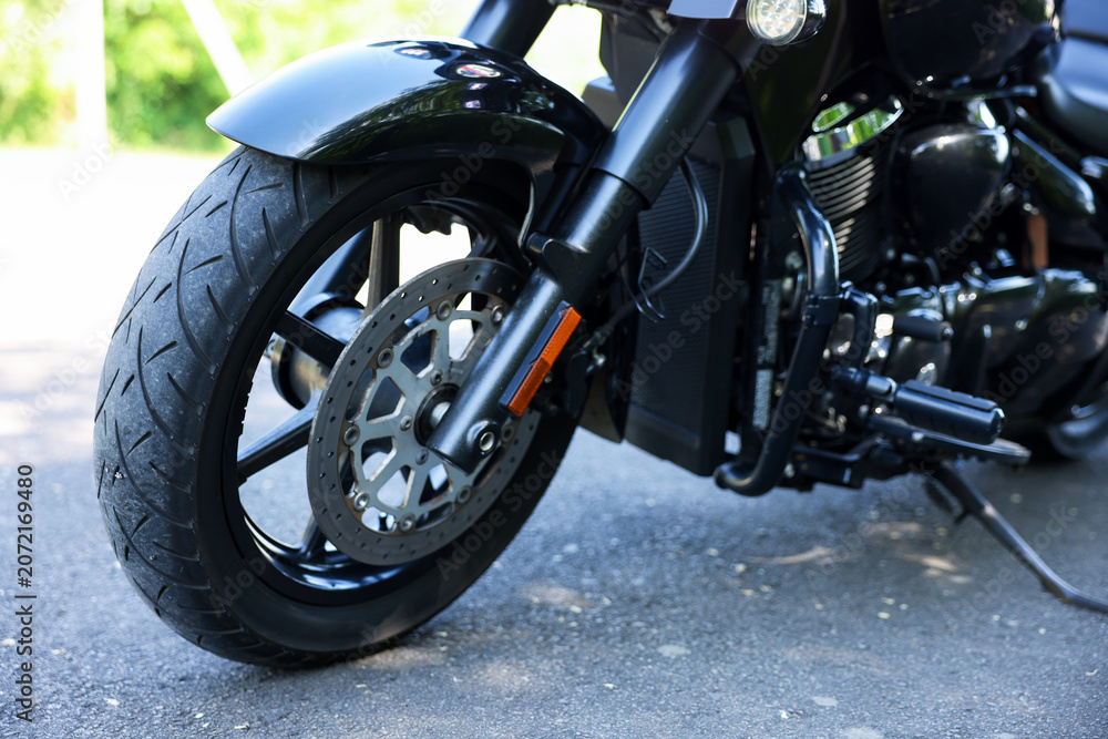 Obraz premium Modern black motorcycle parked on road outdoors, closeup