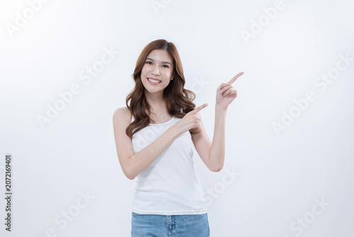 Isolated asian woman smiling and pointing to blank copy space
