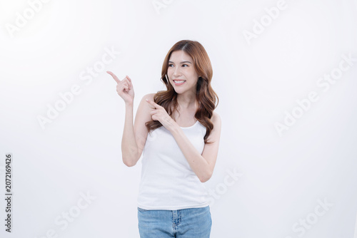 Isolated asian woman smiling and pointing to blank copy space