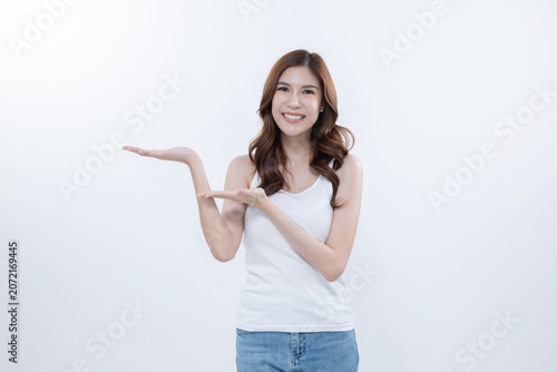 Isolated asian woman smiling and pointing to blank copy space