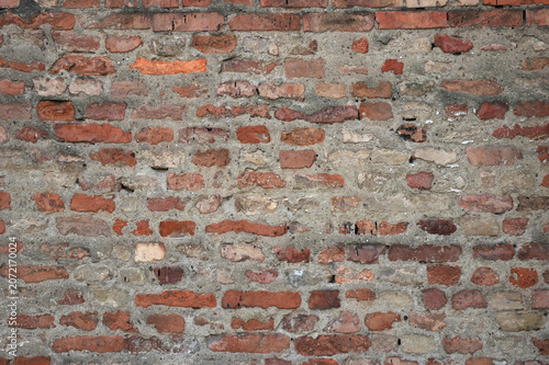 Fotografía Full frame view of an ancient rustic brick wall made of uneven red and orange stones mixed with thick grey concrete mortar joints