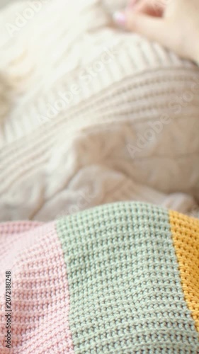 Vertical video: Entering frame, woman's hand smoothing cream throw on bed, arranging pastel blanket
